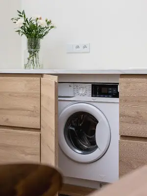 a washing machine in a kitchen with a vase of flowers at 3 bedroom apartment - Rejtana 10 in Kraków