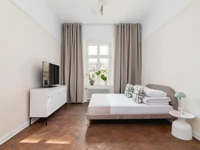 a white bedroom with a bed and a television at 3 bedroom apartment - Rejtana 10 in Kraków