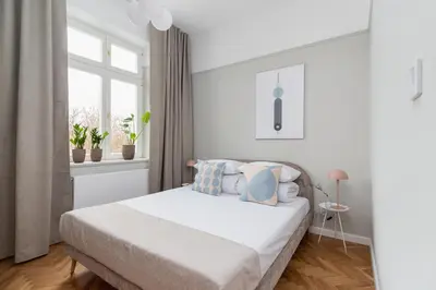 a white bedroom with a bed and a window at 3 bedroom Apartment with the balcony - Rejtana 10 in Kraków