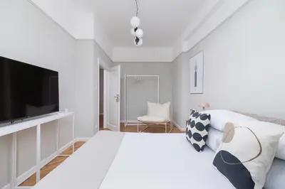 a white bedroom with a large bed and a flat screen tv at 3 bedroom Apartment with the balcony - Rejtana 10 in Kraków