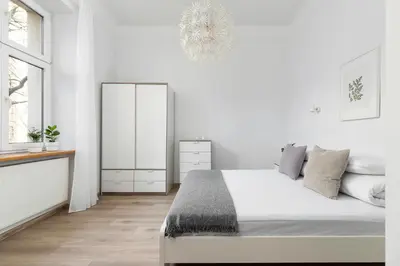 a white bedroom with a bed and a mirror at 1 Bedroom Apartment - Ludwika Zamenhofa 6 street in Kraków