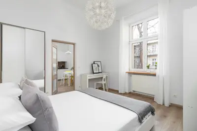a white bedroom with a bed and a mirror at 1 Bedroom Apartment - Ludwika Zamenhofa 6 street in Kraków