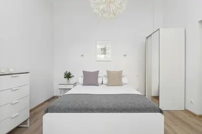 a white bedroom with a large bed and a chandelier at 1 Bedroom Apartment - Ludwika Zamenhofa 6 street in Kraków