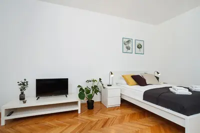 a white bedroom with a bed and a flat screen tv at 2 bedroom apartment - Old Town - Zwierzyniecka 8 street in Kraków