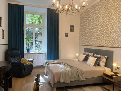 a bedroom with a bed and a chair and a window at Wawel Crown Apartments in Kraków