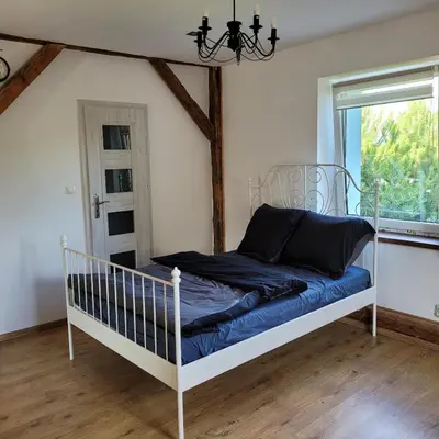 a bedroom with a bed with blue sheets and a window at Dom dla 6 osób in Oświęcim