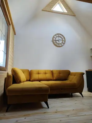 a brown couch in a living room with a clock on the wall at Domek Pocieszna Podkowa in Rabka-Zdroj