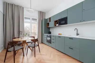 a kitchen with blue cabinets and a table with chairs at 2 - bedroom Apartment with balcony - Rejtana 10 in Kraków