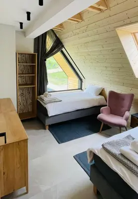a bedroom with a bed and a chair and a window at Szlak By Trafił in Poręba Wielka