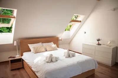 a bedroom with two towels on a bed with two windows at Dom z ogrodem i prywatnym parkingiem w Krakowie in Kraków