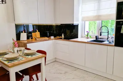 a kitchen with white cabinets and a table and a window at Dom z ogrodem i prywatnym parkingiem w Krakowie in Kraków