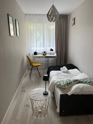 a bedroom with a bed and a table and a chair at Apartament Eva in Kraków