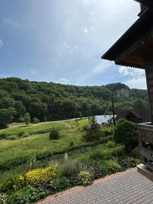 a garden with a view of a river and trees at Leśniewscy - Pokoje Gościnne in Ojców