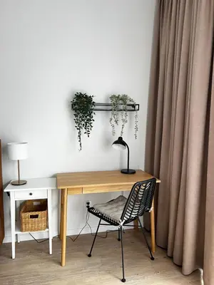 a desk with a lamp and a chair next to a curtain at Sunrise Apartment in Kraków