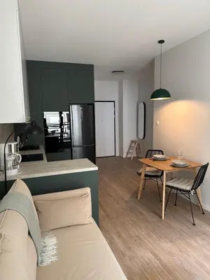 a kitchen and a living room with a table and a couch at Sunrise Apartment in Kraków