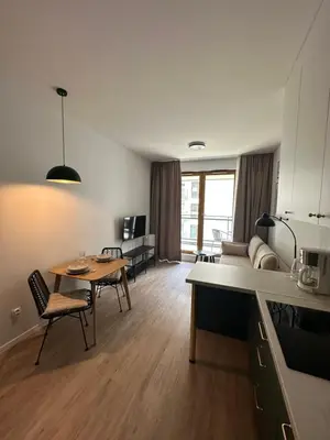 a kitchen and living room with a table and a couch at Sunrise Apartment in Kraków