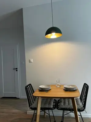 a dining room table with chairs and aendant light at Sunrise Apartment in Kraków