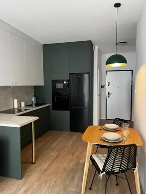a kitchen with a wooden table and a dining room at Sunrise Apartment in Kraków