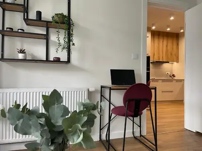 a room with a red chair and a desk with a laptop at Apartament na Krowodrzy in Kraków