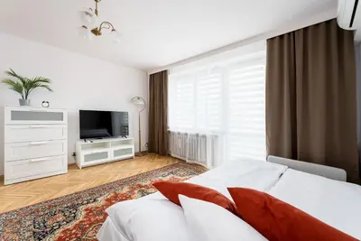 a white bedroom with a bed and a television at Old Town Standard Studio by BookingHost in Kraków