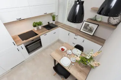 a white kitchen with a table and a clock at Cozy 1-bedroom apartment, Heart of Cracow in Kraków