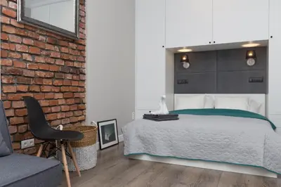 a bedroom with a brick wall and a bed and a chair at Cozy 1-bedroom apartment, Heart of Cracow in Kraków