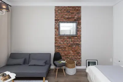 a bedroom with a couch and a brick wall at Cozy 1-bedroom apartment, Heart of Cracow in Kraków
