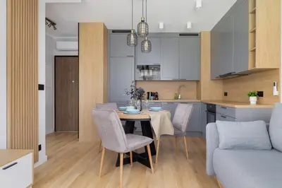 a kitchen and living room with a table and chairs at Elegancki Apartament w Krakowie z Klimatyzacją i Dostępem do Siłowni by Noclegi Renters in Kraków