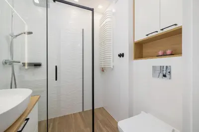 a white bathroom with a glass shower door at Elegancki Apartament w Krakowie z Klimatyzacją i Dostępem do Siłowni by Noclegi Renters in Kraków
