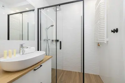a bathroom with a sink and a shower at Elegancki Apartament w Krakowie z Klimatyzacją i Dostępem do Siłowni by Noclegi Renters in Kraków