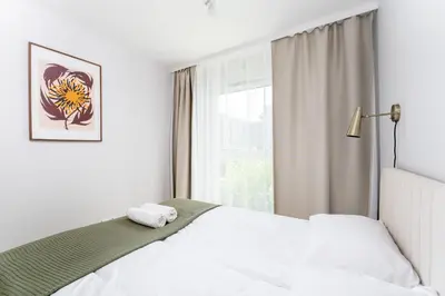 a white bedroom with a bed and a window at Lema Apartment near Tauron Arena in Kraków