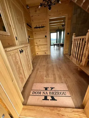 a hallway with a door and a welcome mat on the floor at Dom Na Brzegu in Limanowa