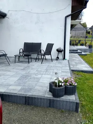 a patio with two chairs and a table and flowers at Świerkowe zacisze 13km energylandia in Wożniki