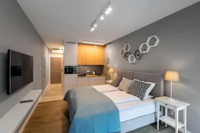 a bedroom with a large bed and a kitchen at Rajska 3 Grey Apartment Krakow City in Kraków