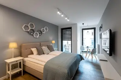 a bedroom with a bed and a tv and a table at Rajska 3 Grey Apartment Krakow City in Kraków