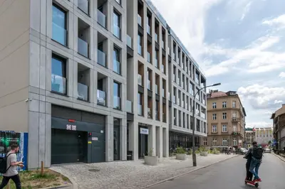 a man riding a skateboard down a street next to a building at Rajska 3 Grey Apartment Krakow City in Kraków