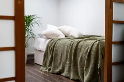 a bed with a green blanket and pillows on it at Malila Premium Apartments Cracow City Center Grodzka 50 in Kraków