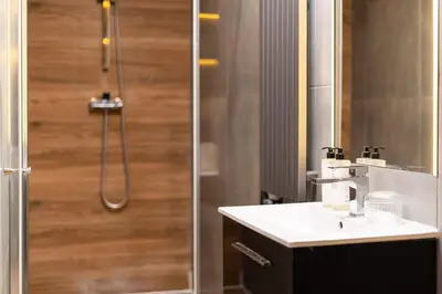 a bathroom with a shower and a white sink at Malila Premium Apartments Cracow City Center Grodzka 50 in Kraków