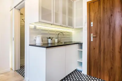 a kitchen with white cabinets and a sink and a door at Old Town Apartments - T36a in Kraków