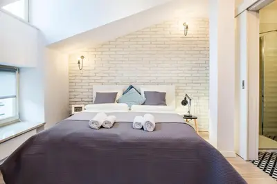 a bedroom with a large bed with two white slippers at Old Town Apartments - T36a in Kraków