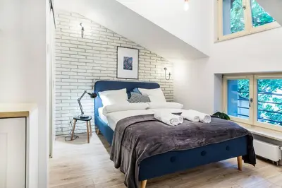 a bedroom with a blue bed and a brick wall at Old Town Apartments - T36b in Kraków
