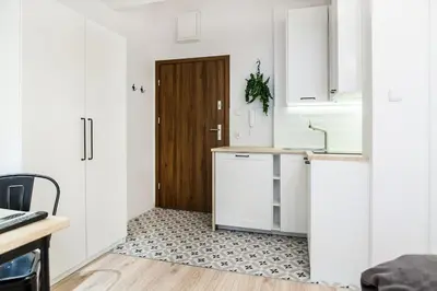 a kitchen with white cabinets and a wooden door at Old Town Apartments - T36b in Kraków