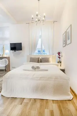 a white bedroom with a large bed with a chandelier at Old Town Apartments - T32 in Kraków