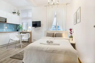 a white bedroom with a large bed and a kitchen at Old Town Apartments - T32 in Kraków