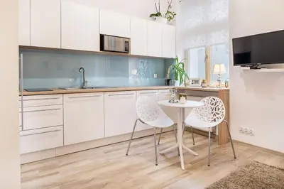a kitchen with white cabinets and a table and chairs at Old Town Apartments - T32 in Kraków