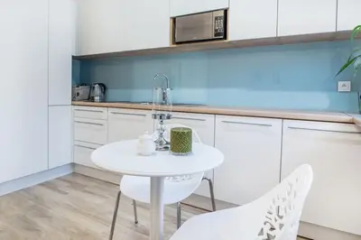 a white kitchen with a white table and chairs at Old Town Apartments - T32 in Kraków
