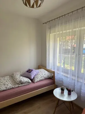 a bedroom with a bed and a window with a table at Domek Babiogórka in Zawoja