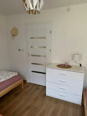 a bedroom with a white dresser and a bed at Domek Babiogórka in Zawoja