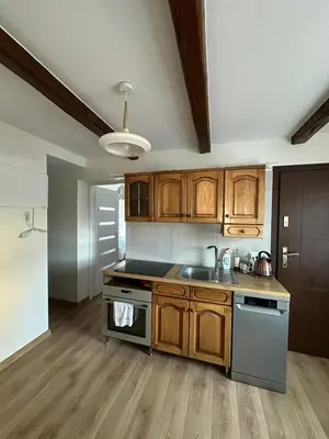 a kitchen with wooden cabinets and a sink and a stove at Domek Babiogórka in Zawoja