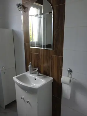 a bathroom with a sink and a mirror and a tub at Pokoje u Ewy in Limanowa